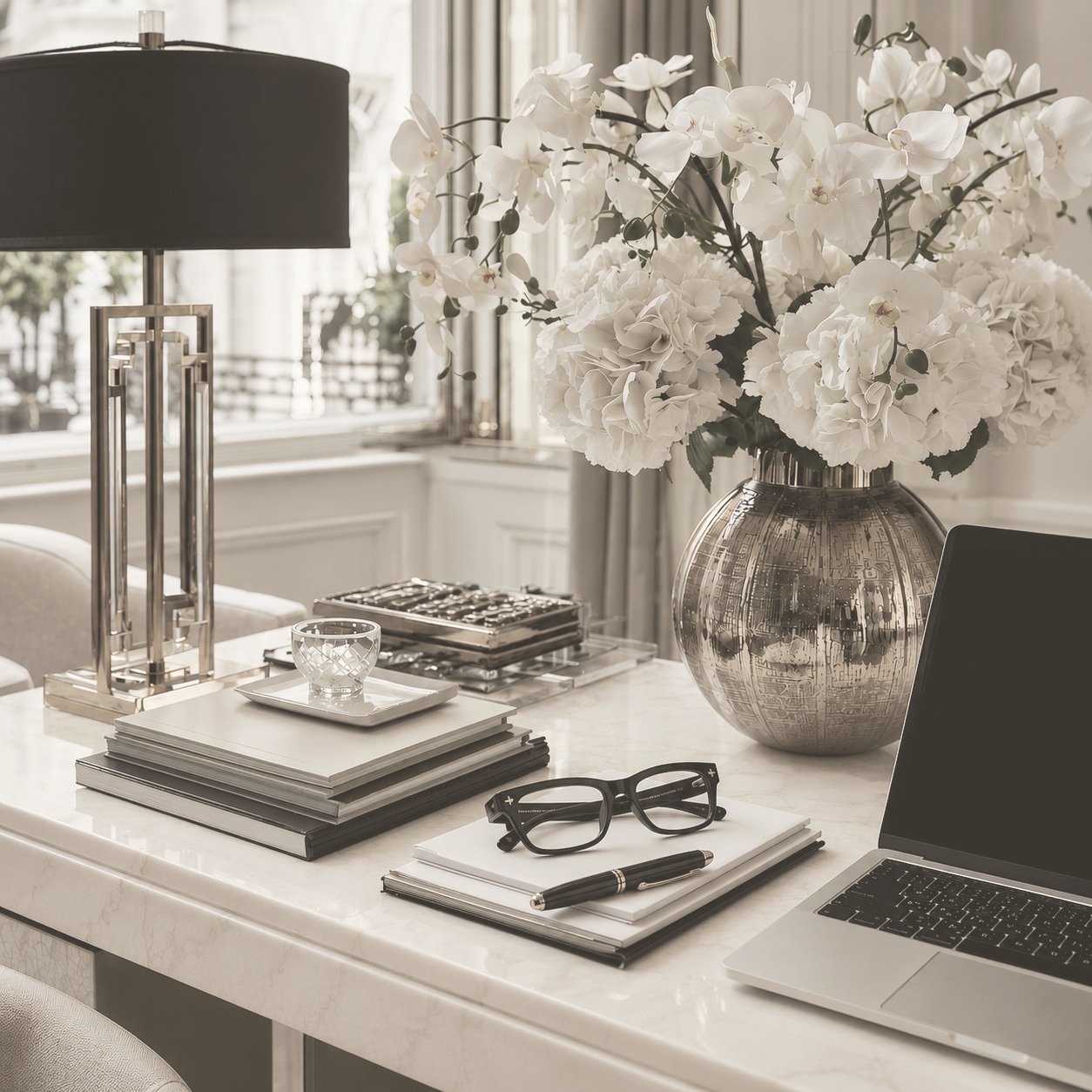 Ivory executive desk with white orchids, gold lamp and a laptop in soft daylight