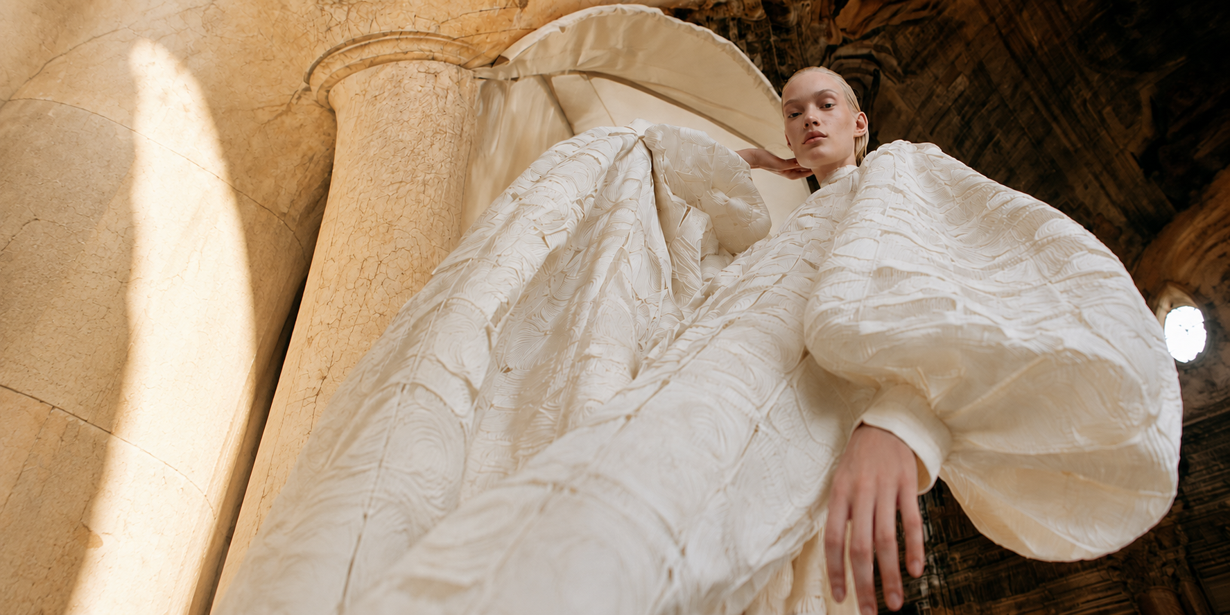A model in sculptural ivory couture beneath travertine columns